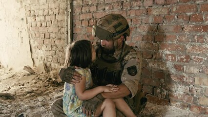 A soldier in a Ukrainian military uniform hugs his little girl with the Ukrainian flag. The concept of saving children from war