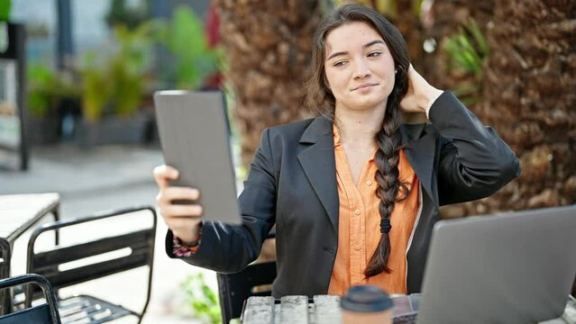 Young beautiful hispanic woman business worker make selfie by touchpad at coffee shop terrace