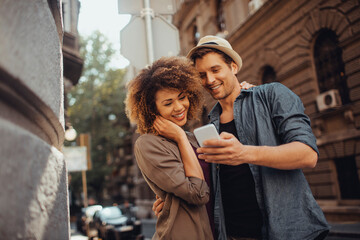 Young couple using a smart phone while traveling and exploring the city on their vacation