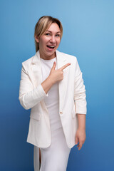 well-groomed young caucasian blond lady in a white jacket and dress points her finger to the sides