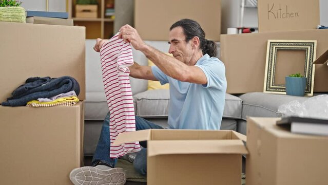 Middle age man unpacking cardboard box at new home