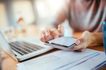 Young woman using a smart phone and laptop at home while working and studying