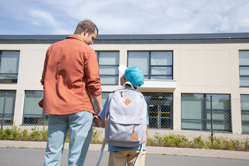 the father takes the boy to school. dad is holding his son's hand. Parental care, return to school,...