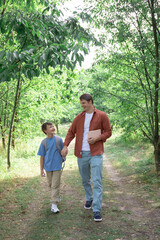 Fototapeta na wymiar happy son and father go to school boy and dad walk through the park and talk. the concept of family, education, back to school, lifestyle