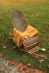 Rocking chair with an orange plaid in the autumn garden. Soft focus