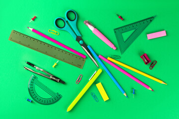 school supplies, rulers, pencils, buttons, pen, compasses, paper clips green background flat lay