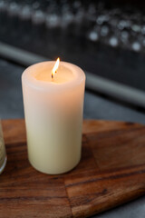 isolated lit candle with glassware in the background