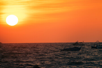 Silhouettes of fishing boats with sunset on the sea. The sun goes down on the sea.