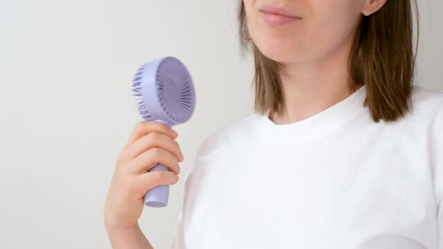 Young woman holding a small fan on white background close-up.