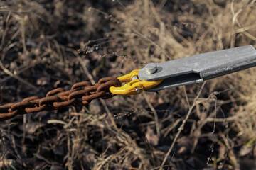Tensioned rusty chain with a bracket. Strong rusty chain in tension