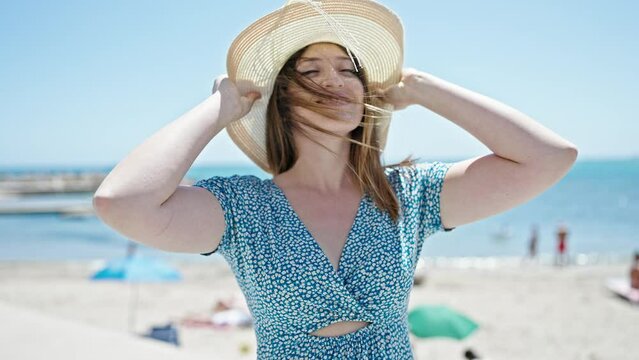 Young blonde woman tourist smiling confident wearing summer hat at seaside