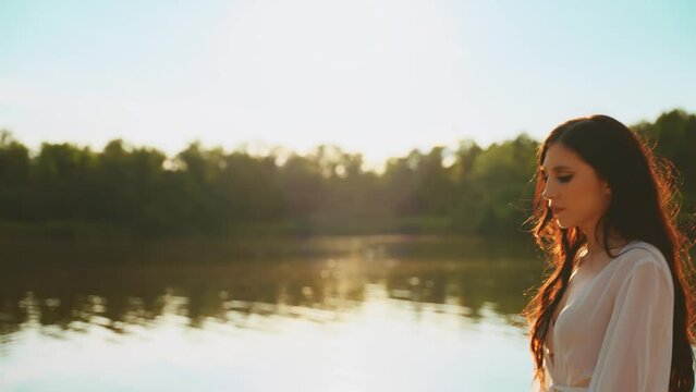 Happy woman beauty face walks along beach river banks beach enjoys summer bright nature free life water magical sun light. Sexy joy Girl in relax calm. white silk dress healthy dark curly long hair 4k