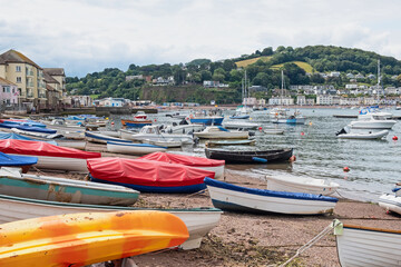 Small fishing boats and leisure craft moored and beached in Teignmouth harbour UK, with the village...