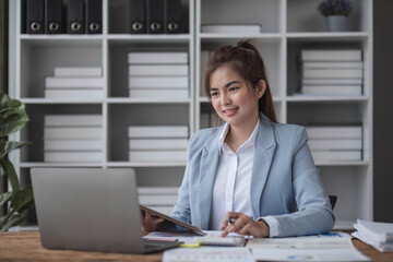 Cheerful business lady working on laptop in office, Asian happy beautiful businesswoman in formal suit work in workplace. Attractive female employee office worker smile