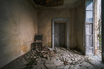 a broken chair with rubble on the floor in an abandoned house