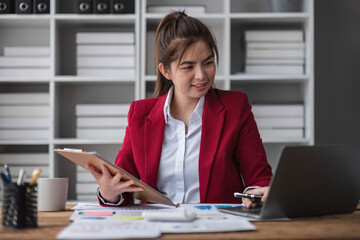 Cheerful business lady working on laptop in office, Asian happy beautiful businesswoman in formal suit work in workplace. Attractive female employee office worker smile