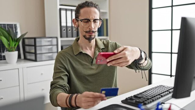 Young hispanic man business worker make photo to credit card by smartphone at office