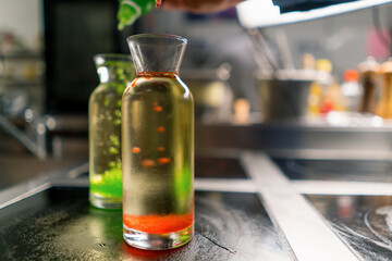 a chef in a professional kitchen experiments by adding multi-colored molecular caviar grains to a...