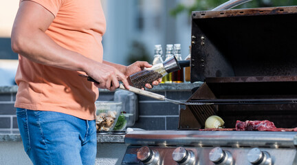 Outdoor man cooking grill and barbecue dishes. Man grilling steaks to perfection on smoky barbecue. Grill tongs at the ready. Grilling man cook meat at barbecue