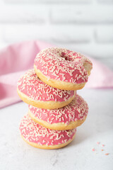 Plate of vanilla cake donuts with pink icing and sprinkles.