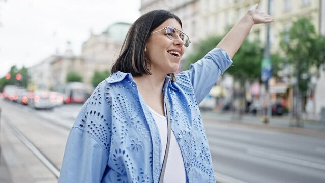 Young beautiful hispanic woman calling for taxi with hand raised in the streets of Vienna