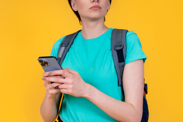 woman with backpack holding smartphone on yellow background. Travel enjoy concept