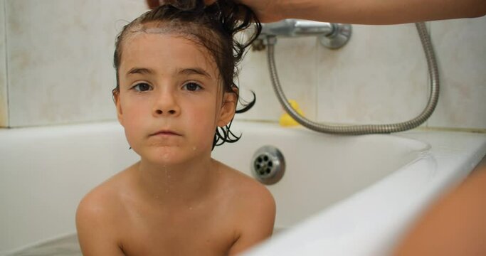 Splash of Love: Witness the Pure Bliss as a Devoted Mother Cleanses Her Child's Hair, Nurturing a Special Bond in the Bath. High quality 4k footage