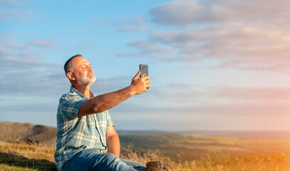 Bearded  man traveler in a blue shirt taveling mountains and taking photos by phone  in Peak District.  Local tourism lifestyle concept.
