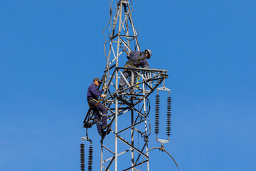 Workers in the electricity sector dismantling a high voltage tower