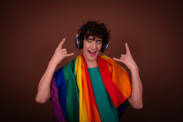 Drag queen with a rainbow flag posing in the studio and listening to music.