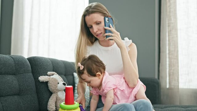 Mother and daughter talking on smartphone while playing with hoops at home