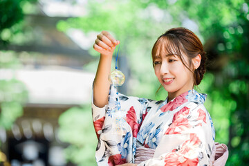 神社で風鈴を持つ浴衣姿の日本人女性