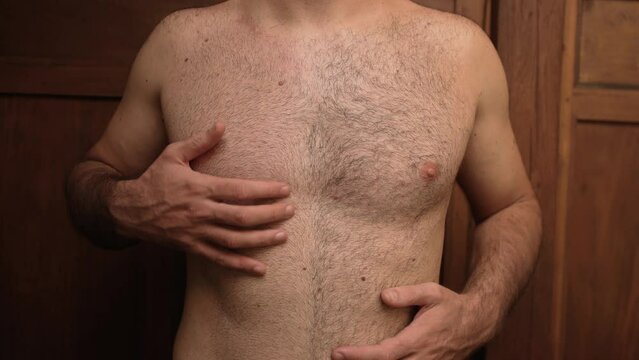 Unrecognizable topless man with a half-shaved body with black thick hair touching his stomach and chest 4K