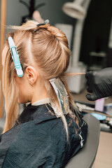 Fototapeta premium The process of hair coloring in a beauty salon. Blonde dyeing her hair