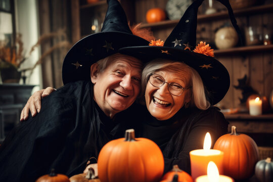 Adorable Couple Of Seniors Celebrating Halloween With Pumpkins And Candles Wearing Costumes.