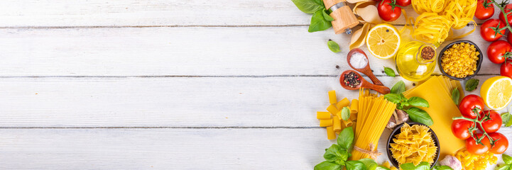 Various pasta with spices and ingredients for cooking. Preparation dinner, lunch background with fresh basil, tomatoes, spices, garlic and different sort and types of italian Mediterranean pasta