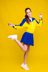cheerleader girl in sports blue and yellow clothes on yellow background