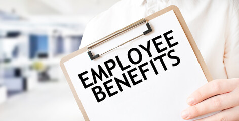 Text EMPLOYEE BENEFITS on white paper plate in businessman hands in office. Business concept