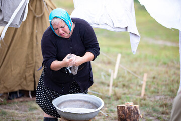  Refugee camp. Refugee woman doing laundry outdoors.