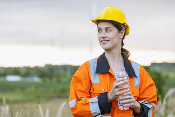 Engineer woman technician standing relax rest drinking clean water after finish service maintenance wind turbine power generator