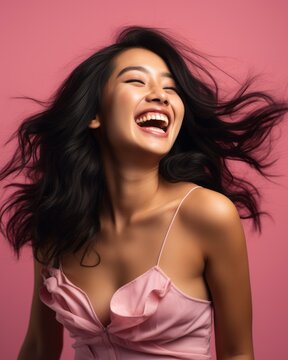 beautiful asian woman laughing with her hair blowing in the wind