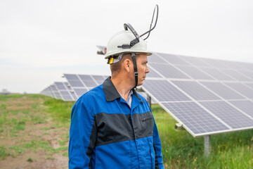 Service Engineer man standing with arms crossed in front of solar panels. Technician maintenance solar cells on Solar Energy Plant under morning sunlight. Technology solar energy renewable