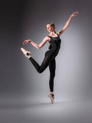Obraz premium Young slender model-looking dancer with long hair in black tight-fitting dancewear in action