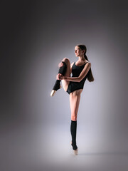 Young slender model-looking dancer with long hair in black tight-fitting dancewear in action