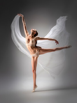 Young slender model-looking dancer with long hair in beige tight-fitting dancewear  in action