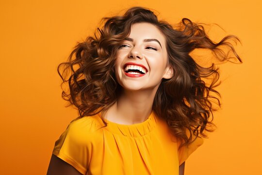 Adorable woman in orange attire touching her brown wavy hair. Laughing blithesome girl posing on yellow background generative AI