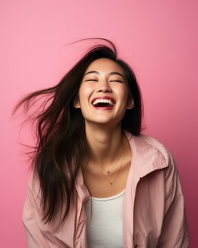 portrait of happy young asian woman laughing isolated on pink background stock photo