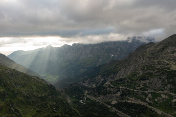 Drone view of majestic Swiss alps with green grass under cloudy sunset sky during sundown time in...