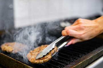 Chef preparing burger at the grill on kitchen