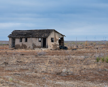 Abandoned house near the ghost town of Yeso, New Mexico with wind turbines in the background